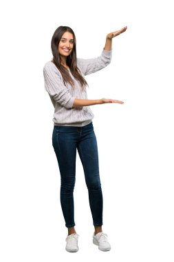A full-length shot of a Young hispanic brunette woman holding copyspace to insert an ad over isolated white background