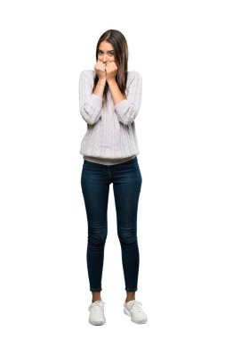 A full-length shot of a Young hispanic brunette woman nervous and scared putting hands to mouth over isolated white background