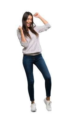 A full-length shot of a Young hispanic brunette woman celebrating a victory over isolated white background