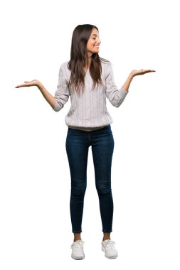 A full-length shot of a Young hispanic brunette woman holding copyspace with two hands over isolated white background