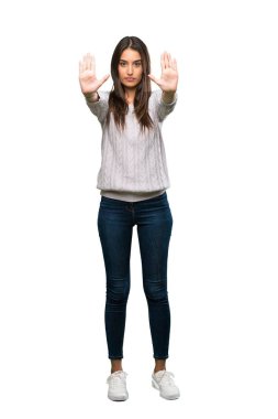 A full-length shot of a Young hispanic brunette woman making stop gesture and disappointed over isolated white background