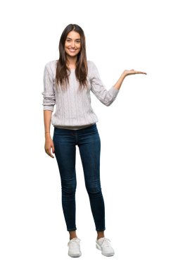 A full-length shot of a Young hispanic brunette woman holding copyspace imaginary on the palm to insert an ad over isolated white background