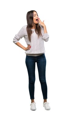 A full-length shot of a Young hispanic brunette woman yawning and covering wide open mouth with hand over isolated white background