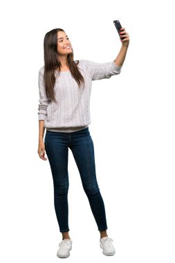 A full-length shot of a Young hispanic brunette woman making a selfie over isolated white background