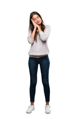A full-length shot of a Young hispanic brunette woman making sleep gesture in dorable expression over isolated white background