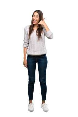 A full-length shot of a Young hispanic brunette woman making phone gesture. Call me back sign over isolated white background