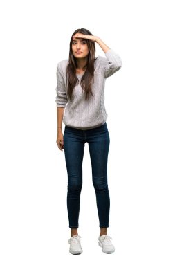 A full-length shot of a Young hispanic brunette woman looking far away with hand to look something over isolated white background