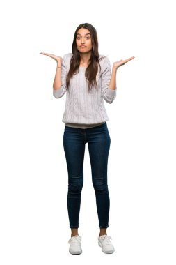 A full-length shot of a Young hispanic brunette woman making doubts gesture over isolated white background