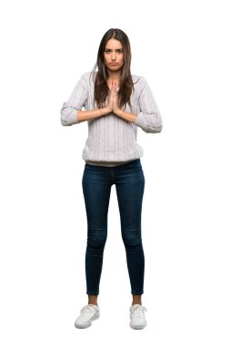 A full-length shot of a Young hispanic brunette woman keeps palm together. Person asks for something over isolated white background