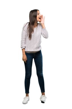 A full-length shot of a Young hispanic brunette woman shouting with mouth wide open to the lateral over isolated white background