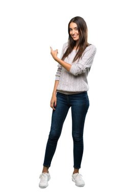 A full-length shot of a Young hispanic brunette woman pointing back over isolated white background