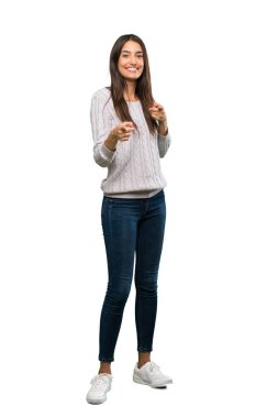A full-length shot of a Young hispanic brunette woman pointing to the front and smiling over isolated white background