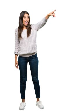 A full-length shot of a Young hispanic brunette woman pointing away over isolated white background