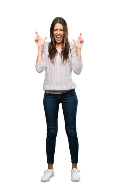 A full-length shot of a Young hispanic brunette woman with fingers crossing over isolated white background