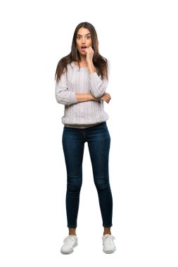 A full-length shot of a Young hispanic brunette woman surprised and shocked while looking right over isolated white background