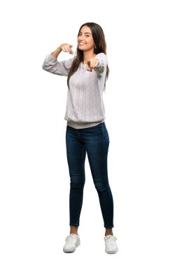 A full-length shot of a Young hispanic brunette woman points finger at you while smiling over isolated white background