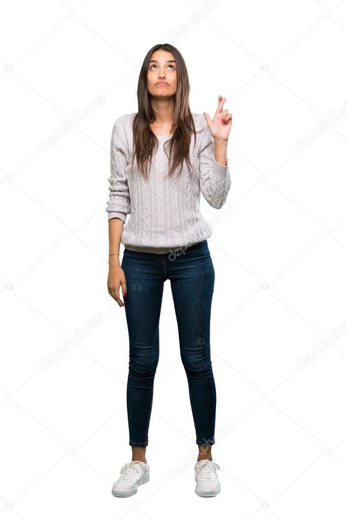 A full-length shot of a Young hispanic brunette woman with fingers crossing and wishing the best over isolated white background