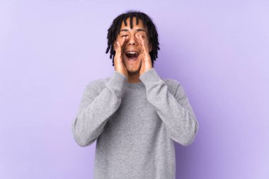 Genç Afrikalı Amerikalı bir adam mor arka planda izole edilmiş bağırıyor ve bir şey duyuruyor.