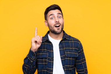 Sarı arka planda sakallı yakışıklı genç adam bir fikir düşünüyor.