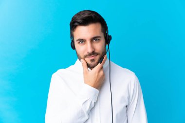 Tele pazarlamacı, izole edilmiş mavi arka plan üzerinde çalışan bir kulaklıkla çalışıyor.