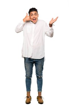 Genç bir adamın telefon jesti yaptığı ve izole edilmiş beyaz arka plandan şüphe ettiği uzun bir çekim.