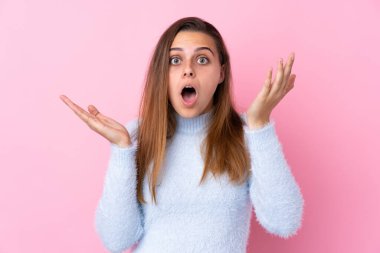 Mavi kazaklı genç bir kız. Soyutlanmış pembe bir arka planı var.