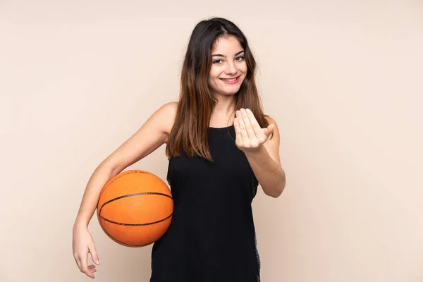 在米色背景下被隔离的年轻的高加索女人打篮球和做即将到来的手势 — 图库照片