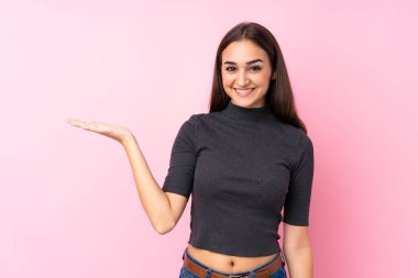 İzole edilmiş pembe arka planı olan genç bir kız, fotokopi alanı hayali bir ilan vermek için avucunun içinde tutuyor.