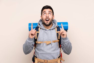 Arka planda izole edilmiş büyük bir sırt çantası olan genç dağcı, işaret parmağıyla işaret etmek harika bir fikir.