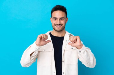 Genç yakışıklı, soyutlanmış mavi arka plan gururlu ve kendini beğenmiş.