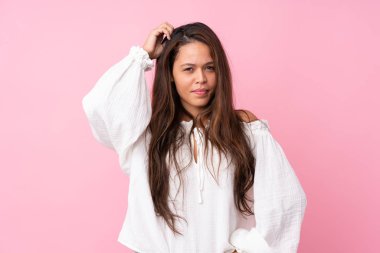 Young Brazilian girl over isolated pink background having doubts while scratching head