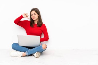 Beyaz arkaplan üzerinde bilgisayar ile çalışan tenaager kız negatif ifade ile başparmak aşağı gösteren