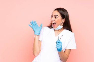 Pembe arka planda yüz ifadesi ile izole edilmiş kadın dişçi aletleri