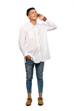 Genç bir adamın izole edilmiş beyaz arka planda cep telefonuyla sohbet ederken tam boy görüntüsü.
