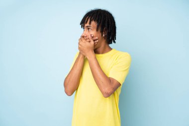 Genç Afro-Amerikan adam mavi arka planda izole edilmiş ağız kaplama ve yan bakıyor