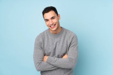 Genç beyaz yakışıklı adam mavi arka planda izole edilmiş gülüyor.