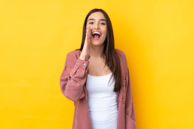 Sarı arka planda genç esmer kadın ağzı açık bağırıyor.