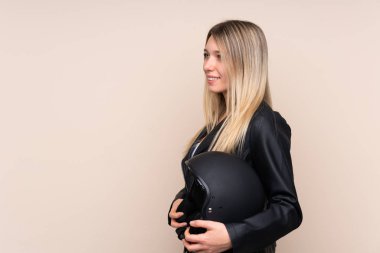 Motosiklet kasklı genç sarışın kadın izole edilmiş arka planda yan tarafa bakıyor.