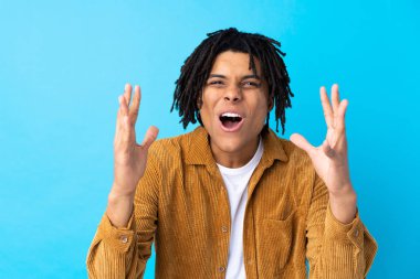Young African American man with corduroy jacket over isolated blue background with surprise facial expression