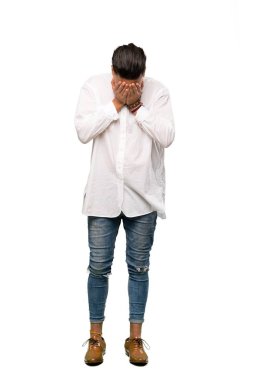 İzole edilmiş beyaz arka plan üzerinde yorgun ve hasta bir ifadeye sahip genç bir adamın tam boy çekimi.