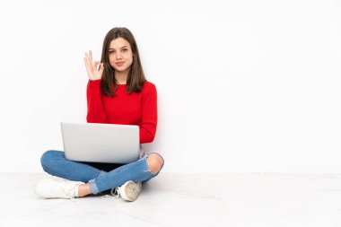 Bilgisayarla çalışan tenaager kız beyaz arkaplanda izole edilmiş, tamam işareti parmaklarıyla gösteriyor