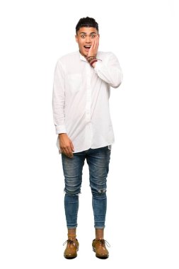 Şaşırmış ve şok olmuş bir yüz ifadesiyle izole edilmiş beyaz arka planda genç bir adamın tam boy çekimi.