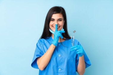 Genç dişçi kadın, mavi arka planda aletleri tutuyor. Sessiz hareketler yapıyor.