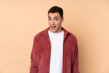 Beyaz tenli yakışıklı adam, bej arka planda izole edilmiş, şaşırmış bir yüz ifadesi var.