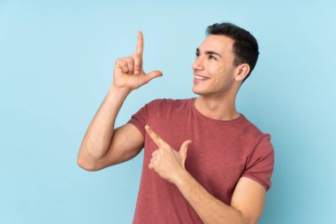 Mavi arka planda izole edilmiş genç beyaz adam işaret parmağıyla işaret etmek harika bir fikir.