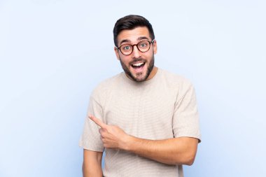 Sakallı, mavi arka planda genç ve yakışıklı bir adam.