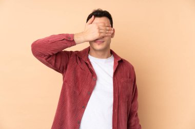 Beyaz tenli yakışıklı adam bej arka planda izole edilmiş gözleri elleriyle kaplayan. Bir şey görmek istemiyorum.