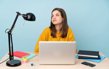 Öğrenci kız evinde çalışıyor. Mavi arka planda izole edilmiş ve araştırılıyor.