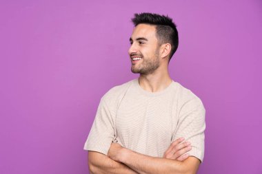 Soyutlanmış mor arka planda genç yakışıklı adam mutlu ve gülümsüyor.