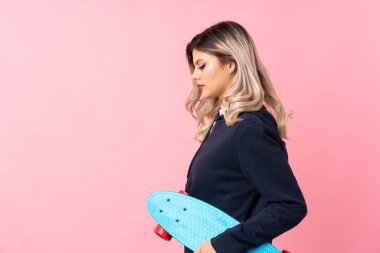 İzole edilmiş pembe arka planda genç kız yan pozisyonda kayıyor.